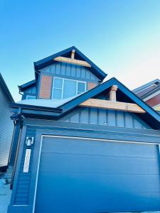 a house with a blue garage door in front of it at Relax at The Hills at Ellerslie in Edmonton