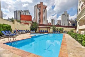 a swimming pool with blue chairs and buildings at Lindo apartamento em São Paulo in Sao Paulo