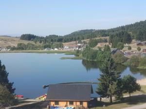 une vue sur un lac avec une maison dans l'établissement Super Besse: Appartement 6 pers. lumineux avec balcon et cuisine équipée - FR-1-814-144, à Besse-et-Saint-Anastaise