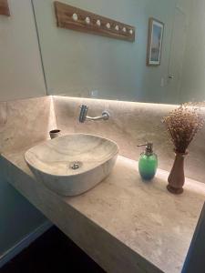 un bancone del bagno con lavandino e vaso di fiori di Aconchego da Praia a Fortaleza