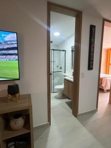 a bathroom with a toilet and a television on a wall at Apartamento en el parque principal con vista a la represa in Guatapé