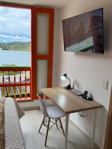 a bedroom with a desk and a bed and a window at Apartamento en el parque principal con vista a la represa in Guatapé