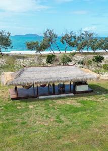 une cabane avec un toit de paille sur une plage dans l'établissement Cottage 2 Cape Keppel Beach, à Curtis Island