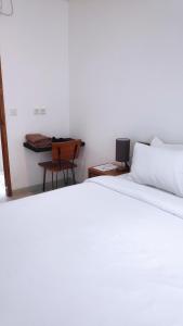 Un dormitorio con una cama blanca y un escritorio. en NOKA ULUWATU BED And BREAKFAST, en Uluwatu