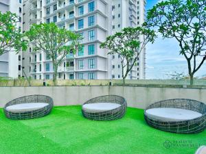drei runde Bänke auf Gras vor einem Gebäude in der Unterkunft Paradigm Residence Johor Bahru by Stayrene in Johor Bahru