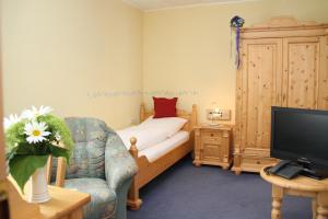 a bedroom with a bed and a tv and a chair at Zilks Landgasthof Zum Frauenstein in Weiding