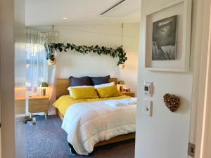 a bedroom with a bed with yellow and blue pillows at Elevated architectural home with stunning sea views in Dunedin
