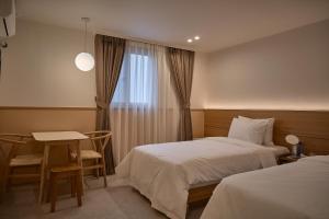 a hotel room with two beds and a table and a window at Stay Libera in Gangneung