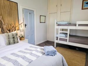 ein Schlafzimmer mit einem Bett und zwei Etagenbetten in der Unterkunft CROOKED MILE COTTAGE - BY THE SEA - family friendly in Hokitika
