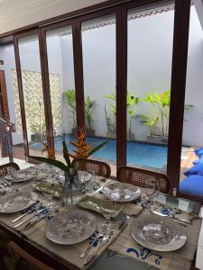 a wooden table with plates and glasses on top of it at New 3BR Villa with Private Pool & Rooftop in Nusa Dua in Nusa Dua