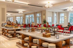 a restaurant with tables and red chairs and people at Legend Valley Hotel Ha Nam in Phủ Lý
