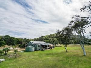 une maison verte au milieu d'un champ dans l'établissement Cottage 4 Cape Keppel Beach, à Curtis Island