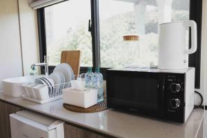 a kitchen counter with a microwave and some dishes at Minshuku 1 by Tiny Away in Chia-tung-wo