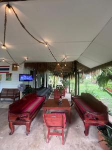 a patio with benches and a table and a tv at Tropical Paradise Leelawadee Resort in Ko Chang