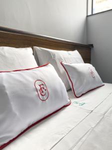 a white bed with red and white pillows on it at FLAT CAMBUCI - Hospedagem e Moradia - Centro de Ipiaú-BA in Ipiaú