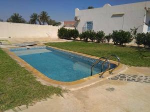 a swimming pool in front of a house at Appartement, séjour Djerba 4 in Arkou
