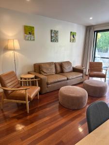 een woonkamer met een bruine bank en stoelen bij The Norgrove By Parbery Property in Kingston 