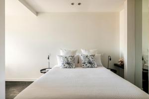 a white bedroom with a large bed with pillows at Sleek&Stylish Corner Apt on TopFloor Southbank Vic in Melbourne