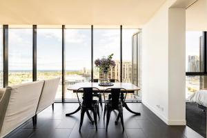 a dining room with a table and chairs and large windows at Sleek&Stylish Corner Apt on TopFloor Southbank Vic in Melbourne