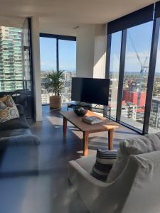 a living room with a tv and a table at Sleek&Stylish Corner Apt on TopFloor Southbank Vic in Melbourne