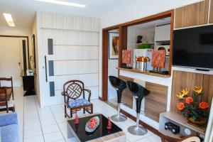 a living room with a flat screen tv and chairs at Alto Estilo Barra Posto 8 in Rio de Janeiro