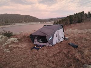 a tent sitting in a field next to a lake at Van near Jindy - Thredbo and ski areas in Jindabyne