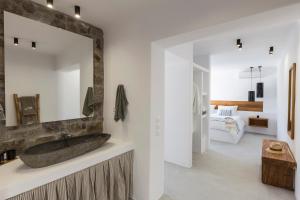 a bathroom with a stone sink and a mirror at Mykonos Panormos Villas in Mykonos