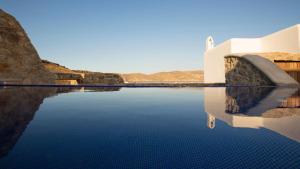 a pool of water in front of a building at Mykonos Panormos Villas in Mykonos