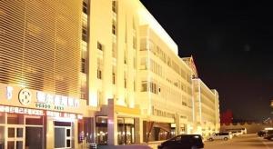 a large building with cars parked in a parking lot at Erdos Great Gate Hotel in Hantai
