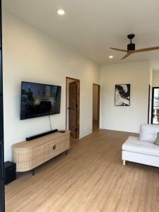 a living room with a couch and a tv on the wall at Chalong Home Phuket in Phuket