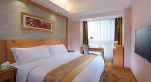 a hotel room with a large bed and a flat screen tv at Vienna Hotel Chengdu Chunxi Road Lijiatuo Metro Station in Chengdu