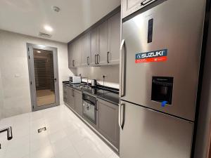 a kitchen with a stainless steel refrigerator and cabinets at Royal Al Arfan Apartment in Muscat