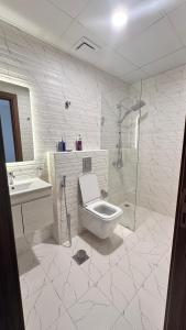 a white bathroom with a toilet and a shower at Royal Al Arfan Apartment in Muscat +8 photos