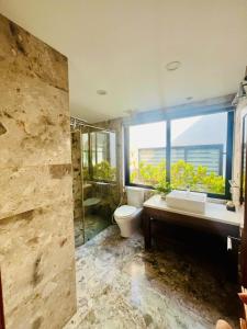 a bathroom with a toilet and a sink and a window at Flamigo Dai Lai Resort - Villa Chủ Tự Doanh in Ngọc Quang