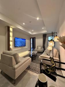 a living room with two chairs and a tv at Royal Al Arfan Apartment in Muscat