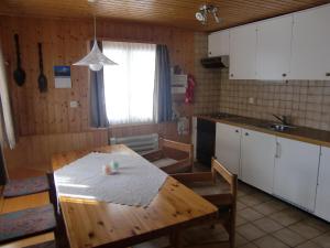 una cucina con tavolo in legno e una cucina con armadietti bianchi di Ferienwohnung Jasmin a Fiesch