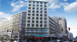 Un edificio alto y blanco en una calle de la ciudad con un semáforo. en City Comfort Inn Shaoyang Wugang, en Wugang