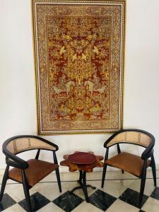 two chairs and a rug on a wall with a tapestry at Mahendra Prakash in Udaipur