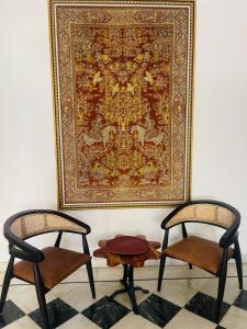two chairs sitting in front of a rug and a picture at Mahendra Prakash in Udaipur