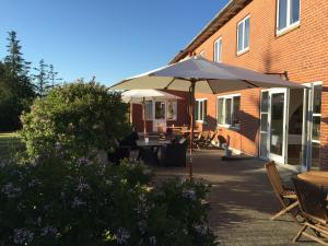 a patio with an umbrella in front of a building at Hotel Strandlyst Badehotel in Hirtshals