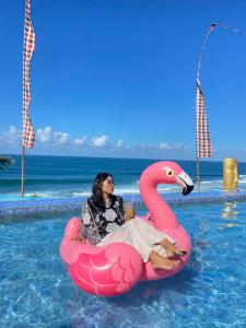 a woman sitting on a pink flamingo in a pool at Osanna Beach Resort Pacitan in Pacitan