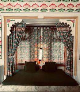 a bedroom with a bed with a window with curtains at Mahendra Prakash in Udaipur