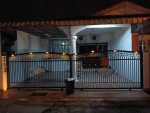 Una puerta de hierro con luces en un porche por la noche. en Anuarosi Homestay Taman Melor, Teluk Intan, en Teluk Intan