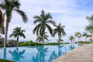 a swimming pool with palm trees in the background at Punta Mita Beachfront Ocean Views BOLONGO in Higuera Blanca