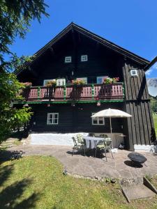 a house with a table and an umbrella in front of it at Knollhäusl in Ramsau am Dachstein +24 photos