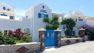 ein weißes Gebäude mit blauer Tür und einigen Pflanzen in der Unterkunft Wisteria Apartments in Karterados