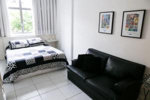 1 dormitorio con 1 cama y 1 sofá de cuero negro en Charmoso Flat em Ipanema, en Río de Janeiro