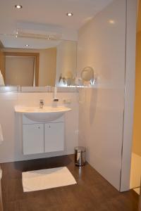 a white bathroom with a sink and a mirror at Hotel Hemetsberger in Attersee am Attersee