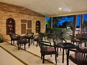 a patio with tables and chairs and a brick wall at Royal Phala Cliff Beach Resort in Ban Chang