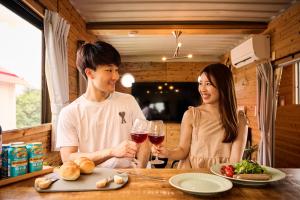a man and a woman sitting at a table with wine glasses at 海辺の古民家 Hug in Nakijin